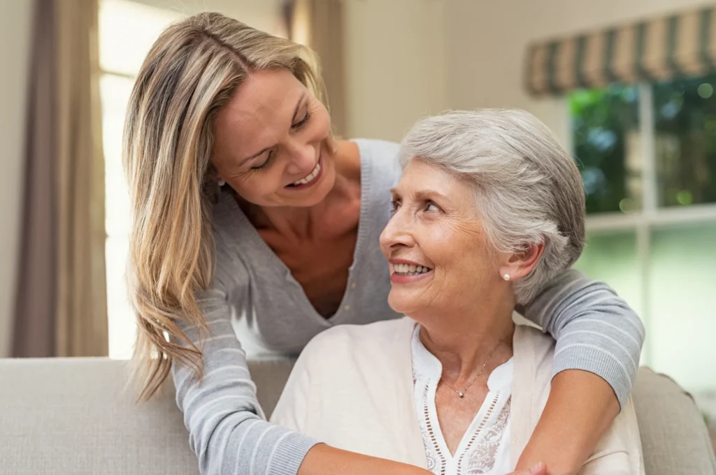Smiling caregiver embracing a senior woman at home