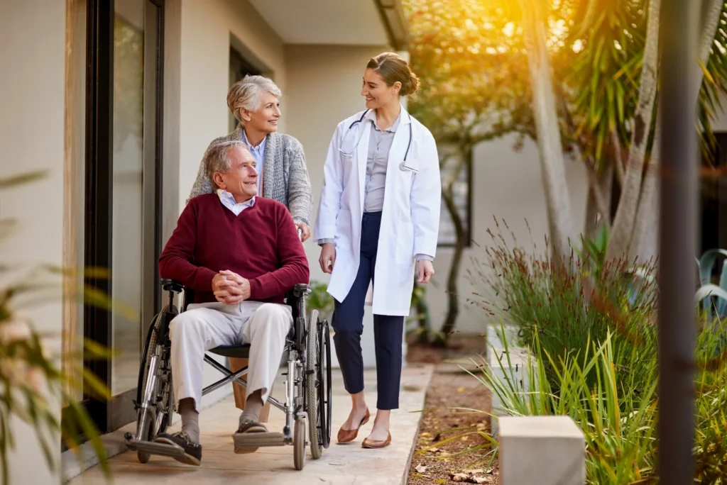 Caregiver assisting a senior man in a wheelchair outdoors