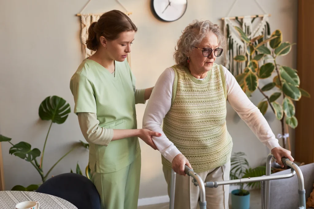 Caregiver helping a senior woman walk safely with a walker at home
